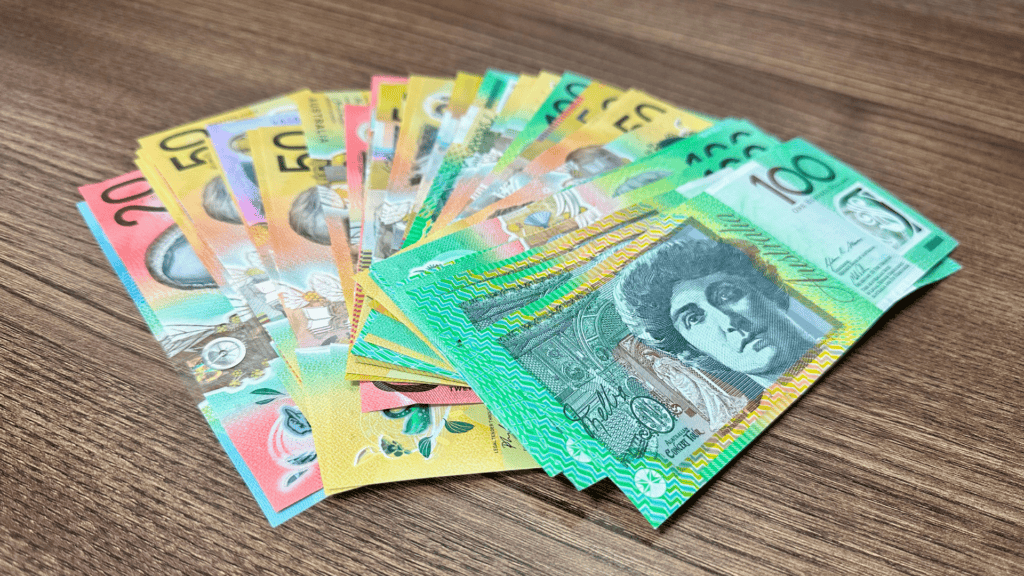 different denominations of polymer Australian Dollar banknotes placed on a wooden table.